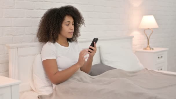 Giovane donna africana che parla su smartphone a letto — Video Stock