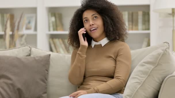 Jong Afrikaans vrouw praten op smartphone op bank — Stockvideo