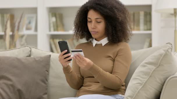 Perda de pagamento on-line no smartphone por mulher africana no sofá Filmagem De Bancos De Imagens Sem Royalties