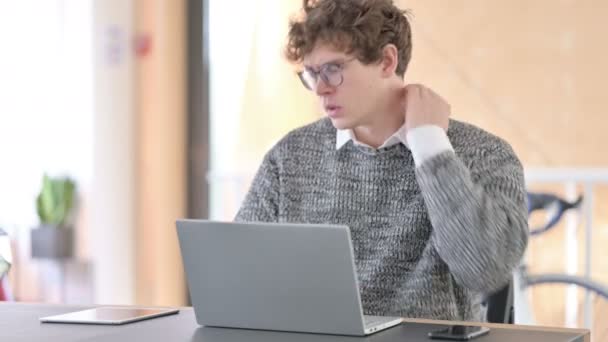 Kreativer junger Mann mit Nackenschmerzen mit Laptop bei der Arbeit — Stockvideo