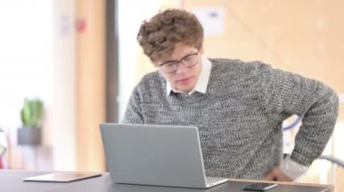 İşte dizüstü bilgisayar kullanan Sırt Ağrısı Olan Yaratıcı Genç Adam 