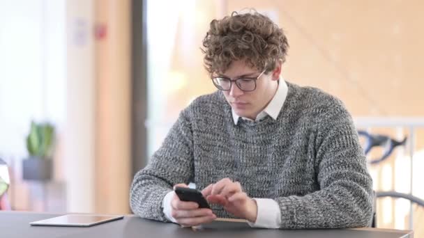 Yaratıcı Genç Adam İş yerinde Akıllı Telefonla Tezahürat Yapıyor, Başarı — Stok video