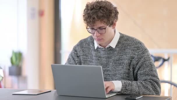 Creatieve jongeman met laptop kijkend naar de camera — Stockvideo