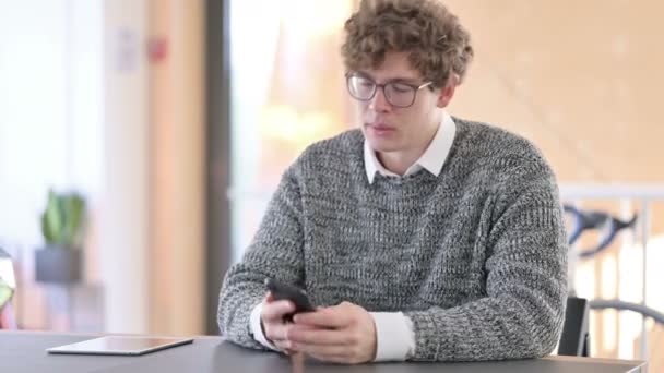 Wütender kreativer junger Mann im Smartphone-Gespräch — Stockvideo