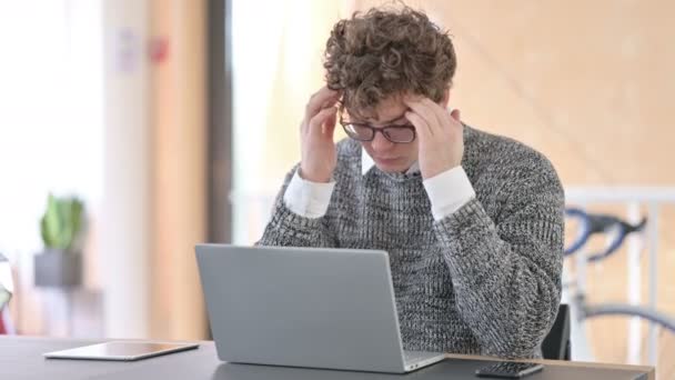 Kreativer junger Mann mit Kopfschmerzen nutzt Laptop bei der Arbeit — Stockvideo