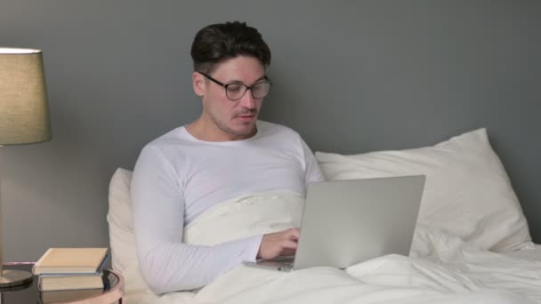 Emocionado hombre de mediana edad celebrando en el ordenador portátil en la cama — Vídeos de Stock