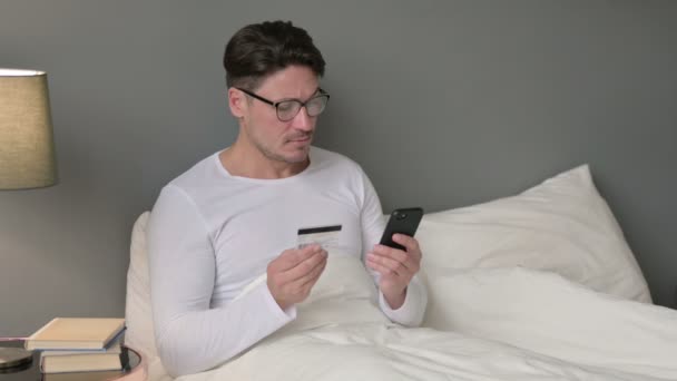 Успех онлайн-оплаты на смартфоне от человека среднего возраста в постели — стоковое видео