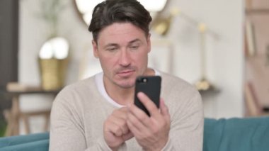 Evde akıllı telefon kullanan orta yaşlı bir adamın portresi 
