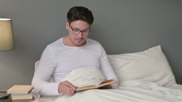 Medelålders man Läsa bok i sängen — Stockvideo