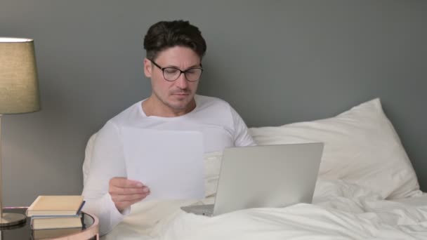 Középkorú férfi a dokumentumok dolgozik Laptop az ágyban — Stock videók