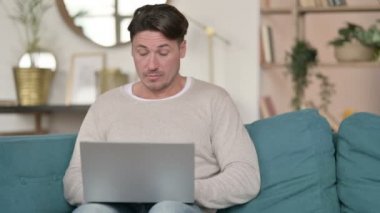 Laptop öksüren orta yaşlı bir adam. 