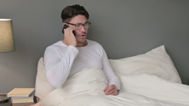 Vzteklý středověký muž mluví na Smartphone v posteli — Stock video