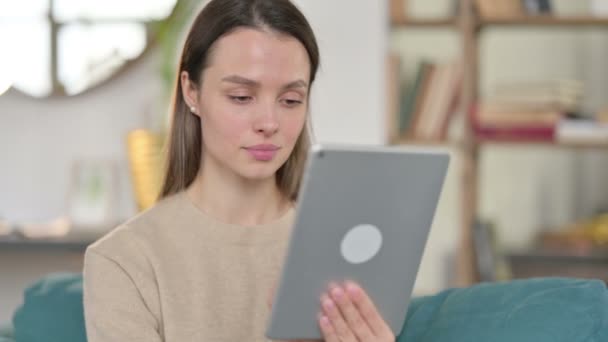 Mladá žena pomocí digitální tablet zatímco sedí na pohovce — Stock video