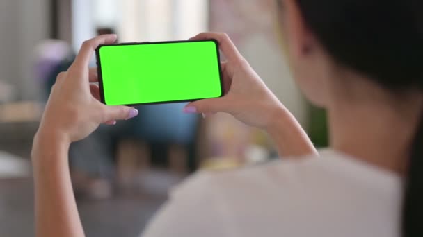 Vista trasera de la mujer latina que mira la pantalla verde del teléfono inteligente, pantalla de croma — Vídeos de Stock