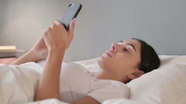 Smartphone kullanımı: Latin Kadın Yatakta Uzanıyor 