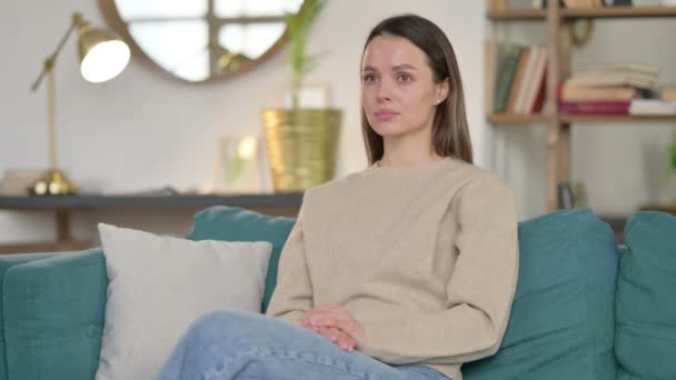 Casual młoda kobieta siedzi na kanapie — Wideo stockowe