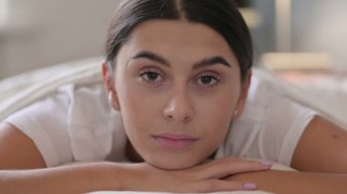 Yatakta uzanmış, kameraya bakan Latin Kadın Portresi 