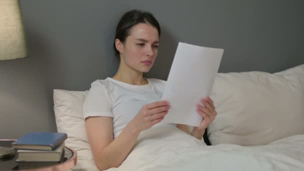 Mladá žena reaguje na ztrátu na dokumenty v posteli — Stock video