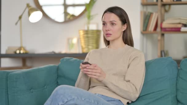 Jeune femme regardant la télévision à la maison — Video