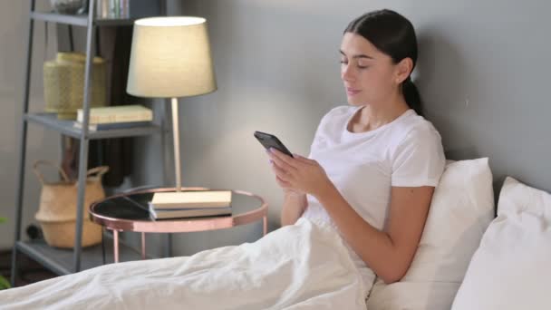 Jovem latina falando no smartphone na cama — Vídeo de Stock