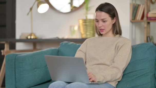 Jeune femme avec ordinateur portable réagissant à l'échec sur le canapé — Video