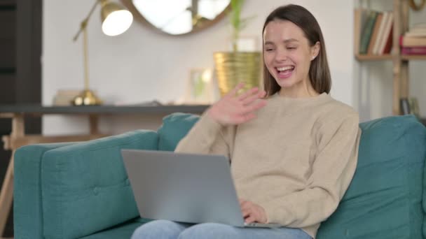 Chat de vídeo en línea en el ordenador portátil por la mujer joven en el sofá — Vídeo de stock