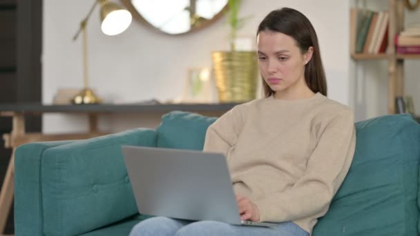 Mujer joven con portátil Pensando en el sofá — Vídeos de Stock