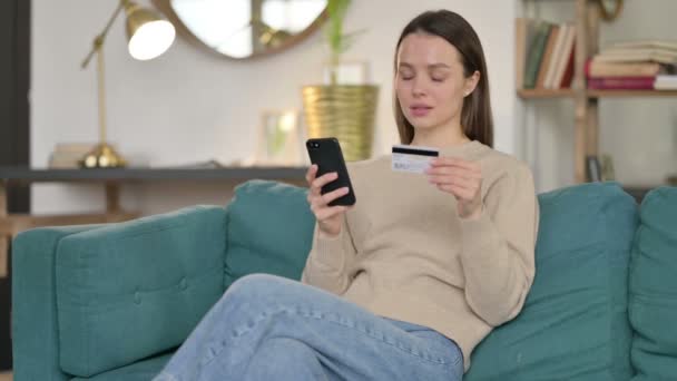 Online nakupování úspěch na Smartphone od mladé ženy na pohovce — Stock video