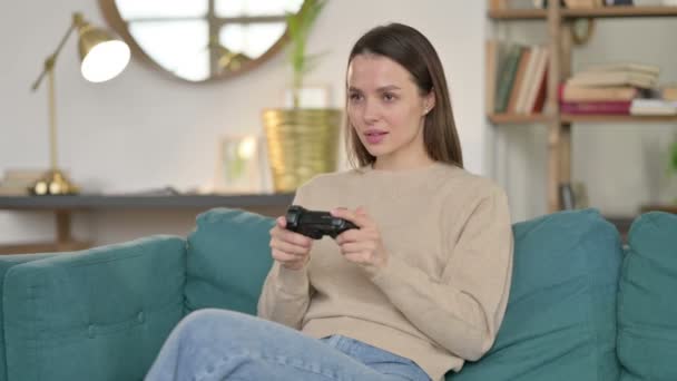 Attraktiv ung kvinna spelar TV-spel på soffan — Stockvideo