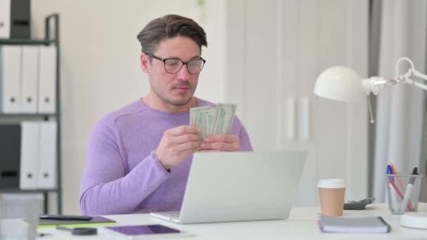 Человек средних лет с ноутбуком Подсчет доллара в офисе — стоковое видео