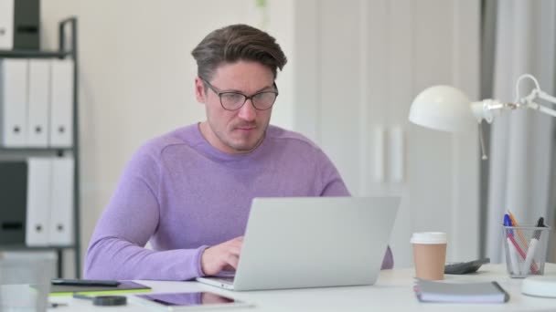 Criativo homem de meia-idade irritado no laptop no escritório — Vídeo de Stock