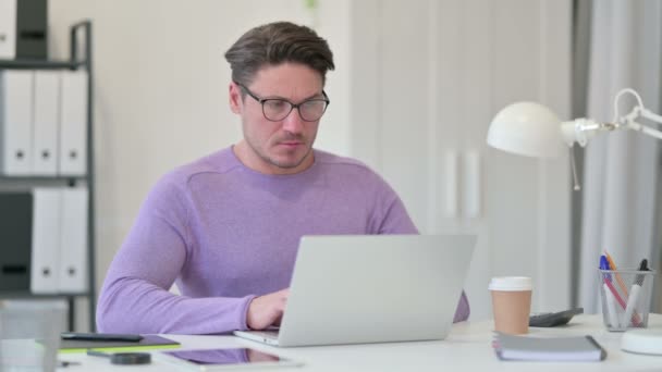 Kreativer Mann mittleren Alters mit Laptop hat Rückenschmerzen im Büro — Stockvideo