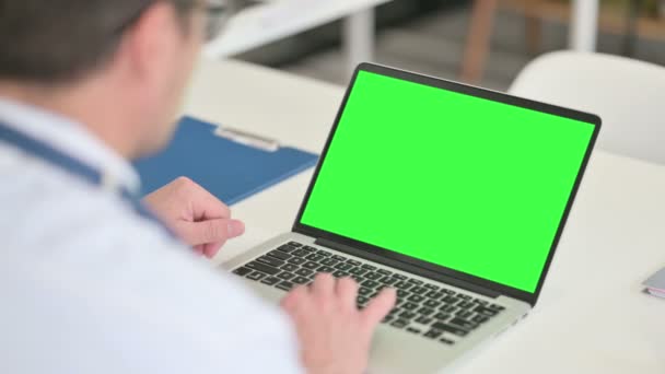 Οπίσθια όψη μεσήλικας αρσενικός γιατρός που χρησιμοποιεί το lap-top με Chroma οθόνη — Αρχείο Βίντεο