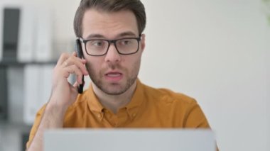 Bilgisayarlı Genç Adam 'ın Akıllı Telefonla Konuşan Portresi 