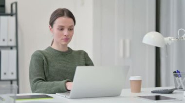 Dizüstü bilgisayarda çalışan genç bir kadın. 