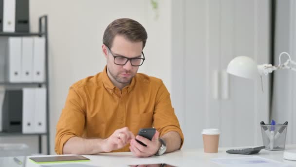 Homem jovem usando Smartphone no escritório — Vídeo de Stock