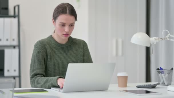 Молодая женщина с ноутбуком чихает в офисе — стоковое видео