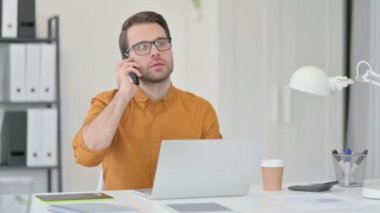 Bilgisayarlı Kızgın Genç Adam Akıllı Telefonla Konuşuyor 