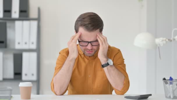 Młody człowiek z bólem głowy w biurze — Wideo stockowe