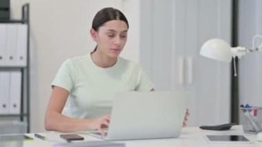 Genç Latin Kadın Kahve içiyor ve laptopta çalışıyor.