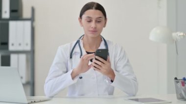 Klinikte akıllı telefon kullanan kadın doktor.