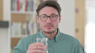 Orta yaşlı adam su içiyor. 