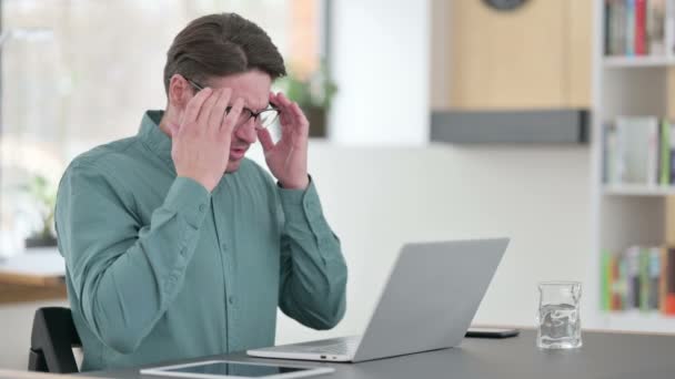 Mann mittleren Alters hat Kopfschmerzen bei der Arbeit am Laptop — Stockvideo