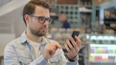 Kafe 'de akıllı telefon kullanan genç adamın portresi