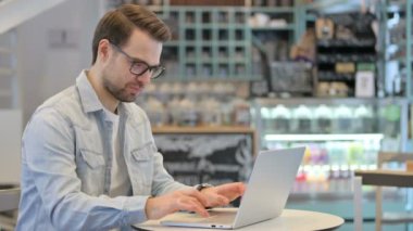 Cafe 'de dizüstü bilgisayarda kutlama yapan başarılı yaratıcı adam.