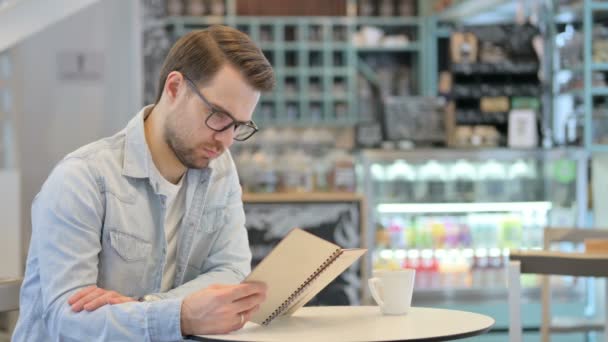 Hombre creativo leyendo libro en Café — Vídeo de stock