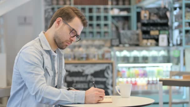 Hombre creativo escribiendo en cuaderno, pensando — Vídeos de Stock