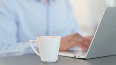 Laptop 'ta çalışan ve kahve içen Afrikalı adam.