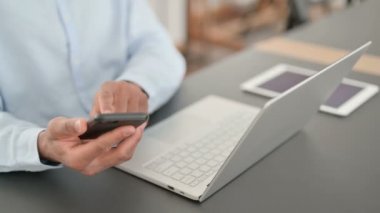 Akıllı telefon ve dizüstü bilgisayar kullanan Afrikalı adamın elleri.