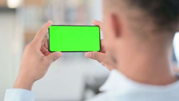 Αφρικανός άνθρωπος βλέποντας Smartphone με την πράσινη βασική οθόνη Chroma — Αρχείο Βίντεο